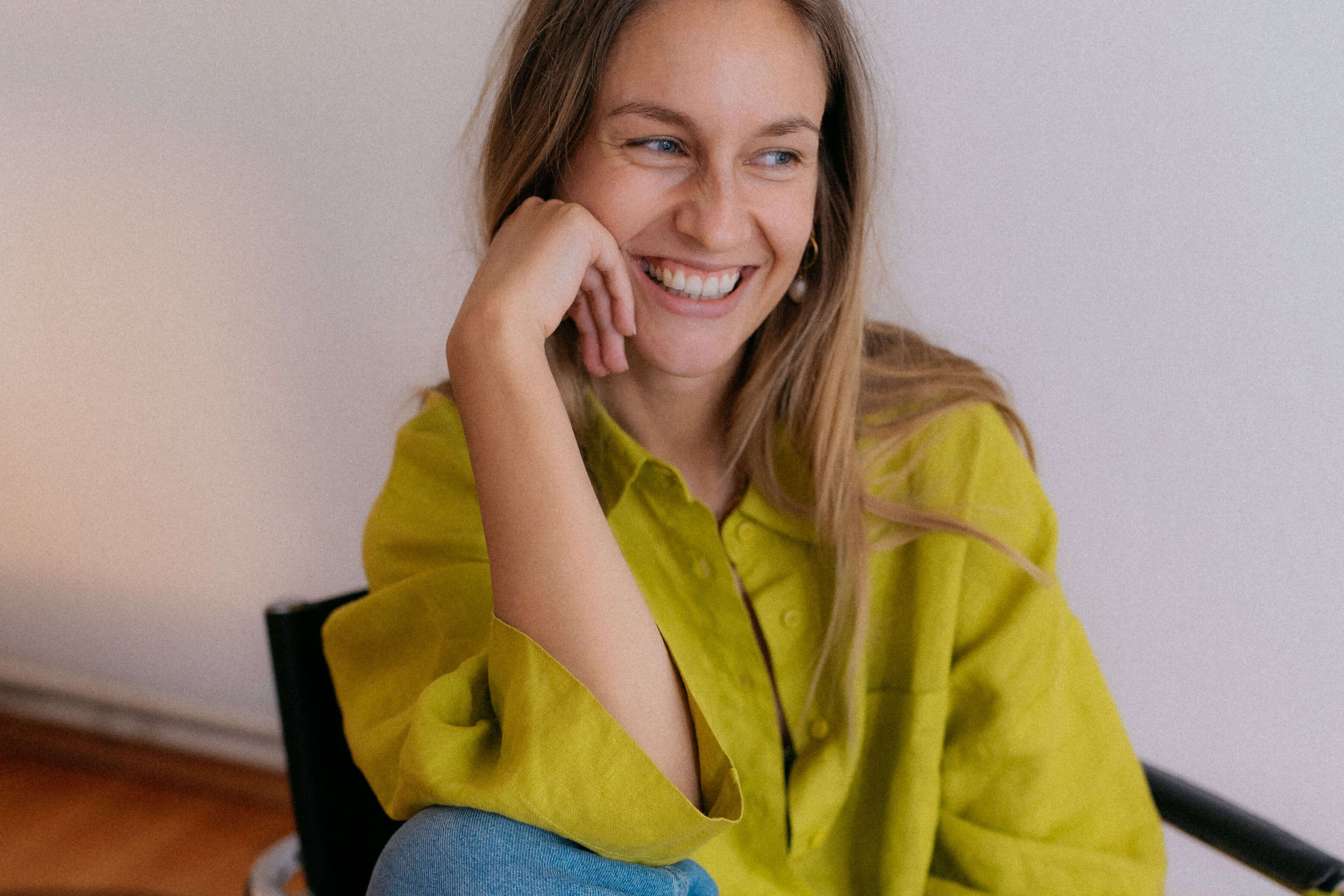 Nina sitzt lächelnd auf einem Bürostuhl